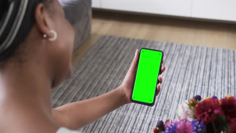 mujer afroamericana sosteniendo un teléfono inteligente con espacio de copia en la pantalla verde