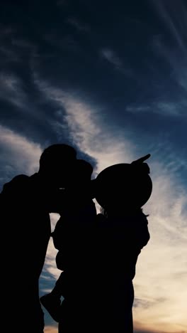 Heartwarming Family Moments Captured at Sunset Silhouettes of Parents and Children Gazing at the Sky Captured at Dusk Silhouettes of a Family Standing in a Beautiful Landscape Sharing Kisses under the Colorful Sky a Heartwarming Scene of Love and Connection Perfect for an Art Poster