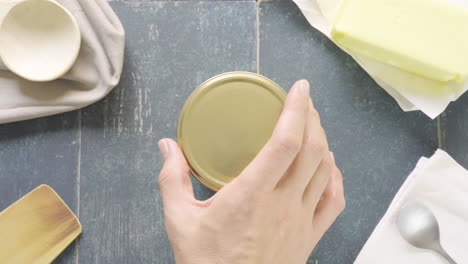 man's hand opens pot of ghee butter