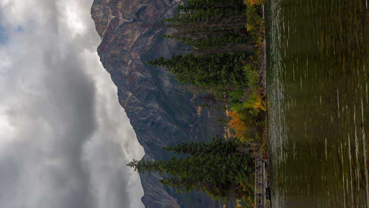 lapso de tiempo vertical de 4k, isla piramidal y puente sobre el lago piramidal, nubes oscuras dramáticas moviéndose sobre los picos del parque nacional jasper, canadá