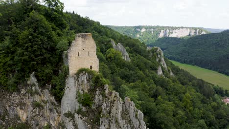 aerial of castle ruin on hill surrounded by forest in south germany