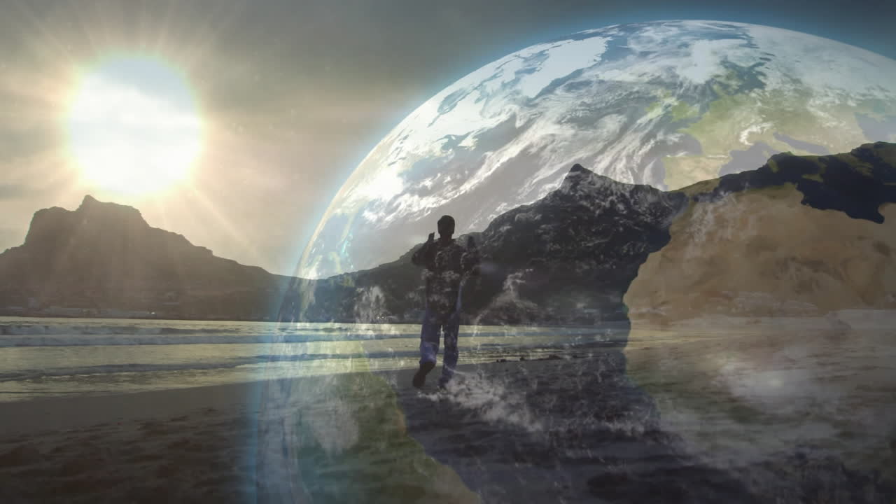 Adult man standing on beach raising arms facing sea, showing sun rays and globe overlay technology