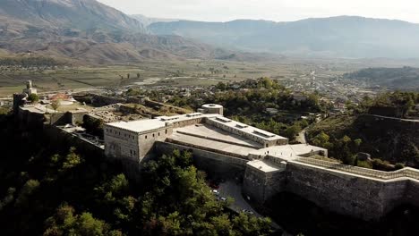 Drone-view-of-Gjirokaster-Castle,-Albania,-Balkans,-Europe-Dolly-shot-of-fort-with-mountains-in-the-background