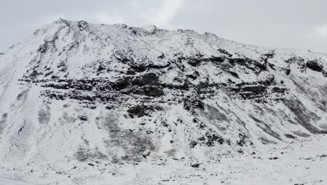 Antenne:-Schneeweißer-Berg-Mit-Schwarzen-Felsen-In-Island-Winter,-Schneit,-Kalt,-Arktisch