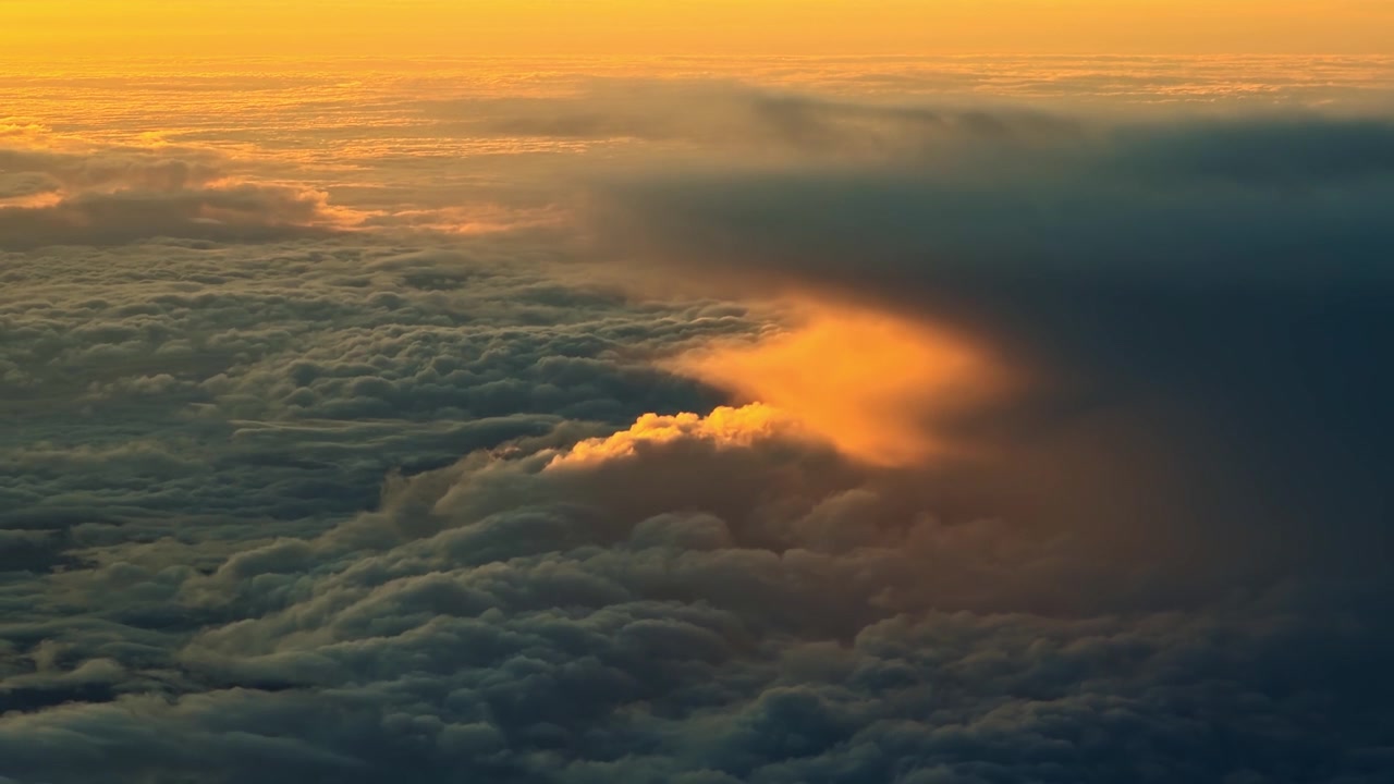 Clouds glow with golden hues as the sun sets, creating a dramatic sky. Ideal for atmospheric scenes or nature documentaries.
