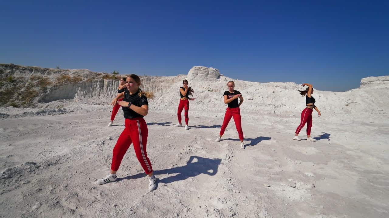 Group of young women dancing outdoors in a desert landscape
