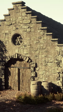 old stone building with wooden doors and barrels