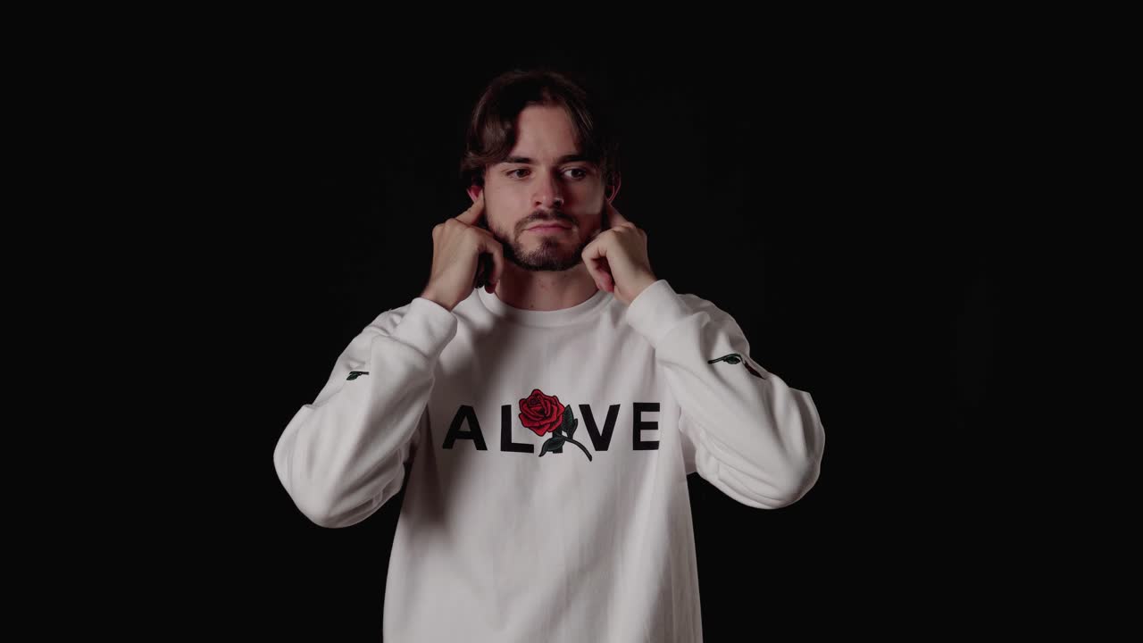 손가락으로 귀를 덮고 기다리고, 넓고, 검은 배경을 가진 트렌디한 청년