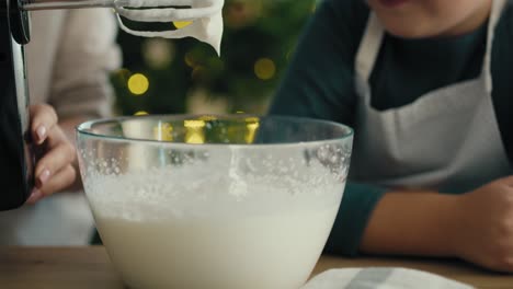 Caucasian-mother-and-daughter-preparing-baking-using-electric-mixer-and-later-tasting.