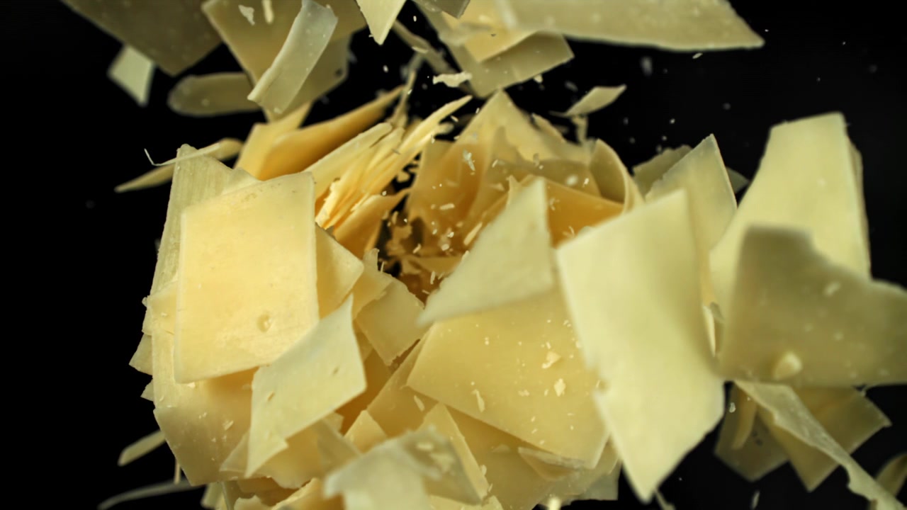 Parmesan Cheese Flakes Falling in Slow Motion on Black Background