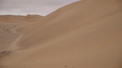 Wind-slowly-blowing-loose-sand-on-a-golden-dune-in-the-Namib-desert