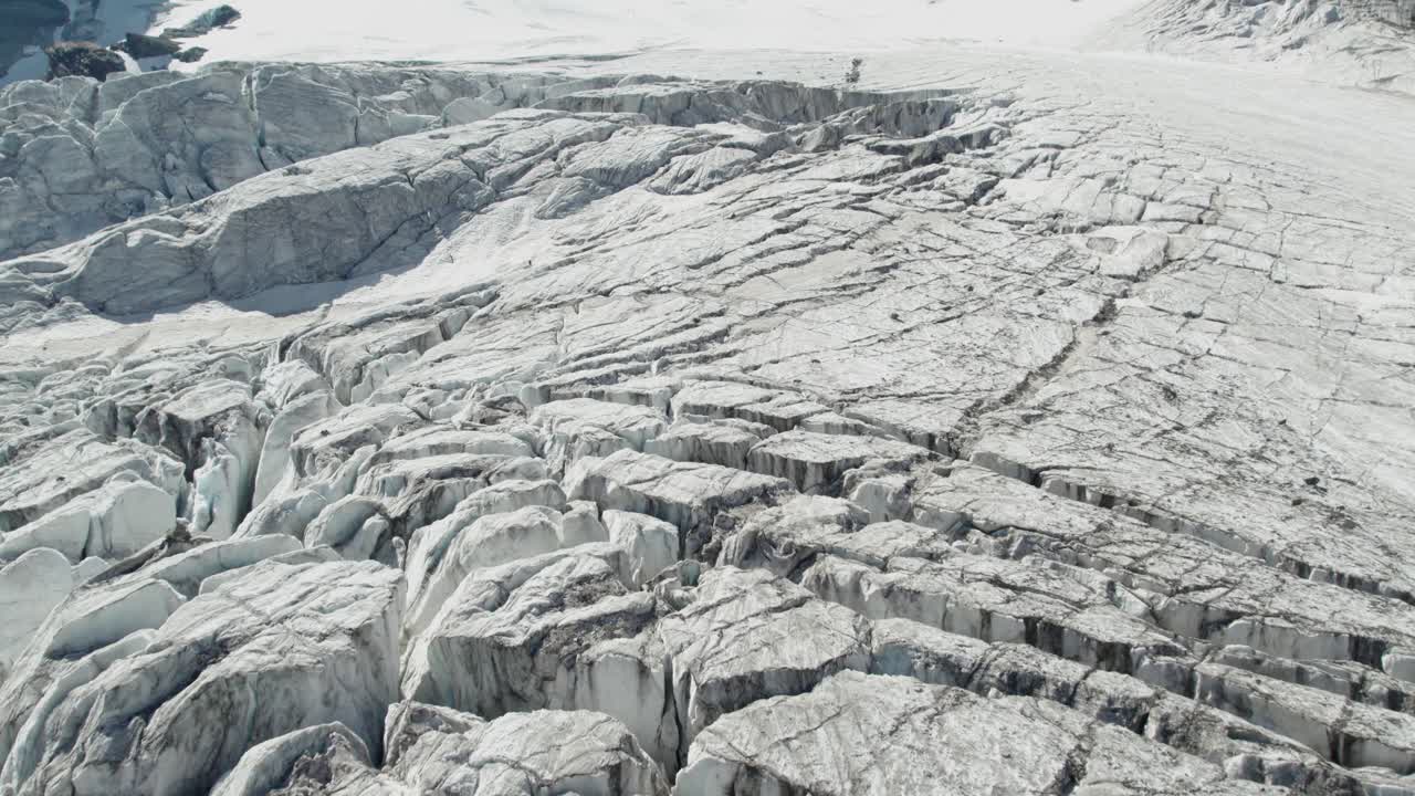 Voo de drone sobre geleira de montanha com fendas, evidenciando o degelo da geleira durante o verão devido ao aquecimento global. Sobrevoo aéreo do Allalingletscher, Suíça