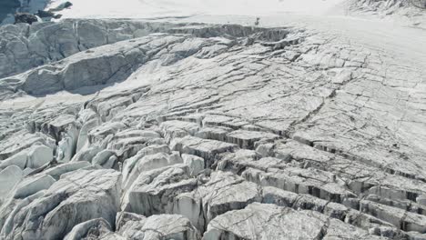 drohnenflug über eisgebirgsgletscher mit gletscherspalten, gletscherschmelze im sommer aufgrund der globalen erwärmung, luftüberflug des allalingletschers in der schweiz