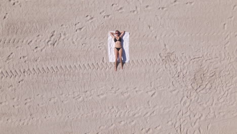 Junge-Kaukasische-Frau-Im-Bikini-Liegt-Auf-Einer-Weißen-Decke-Am-Sandstrand