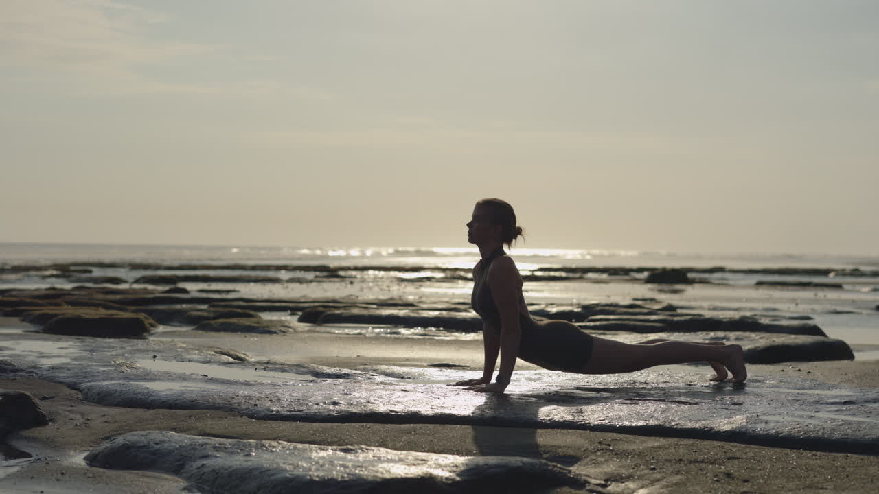 Donna che pratica yoga sulla spiaggia all'alba