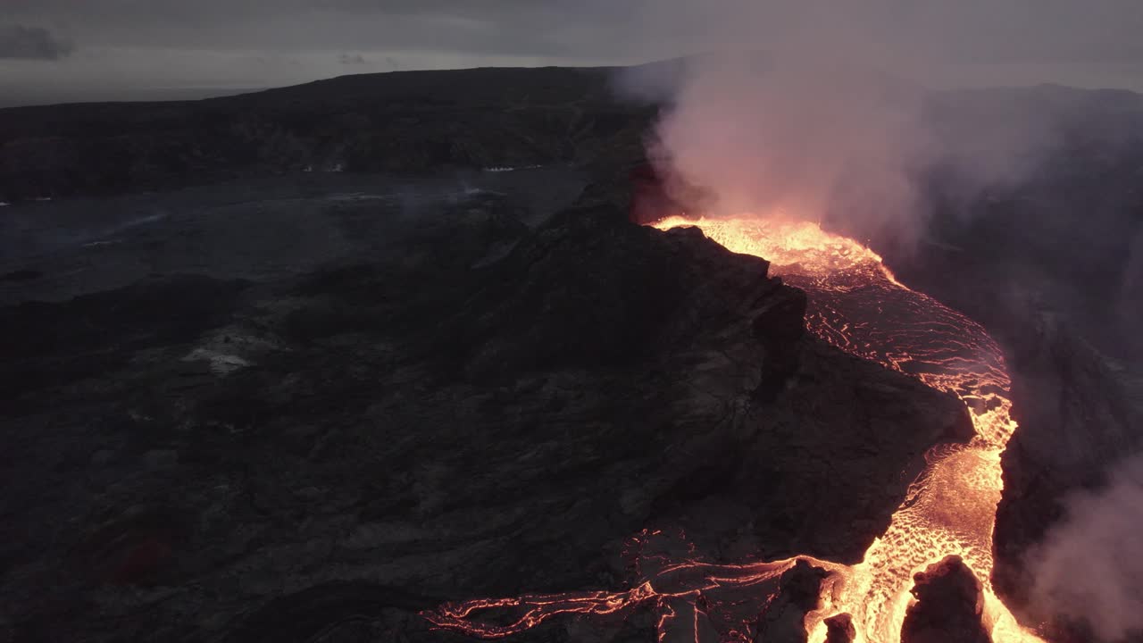 Aerial drone view towards a splattering magma crater, active Volcano surface
