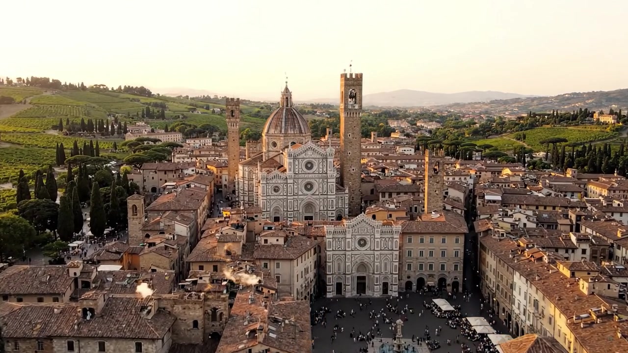 Vista aerea di architettura storica circondata da rigogliosi vigneti verdi al tramonto in un pittoresco borgo italiano.
