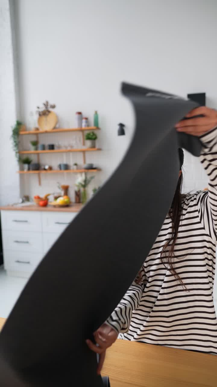 una mujer joven doblando la ropa en una cocina