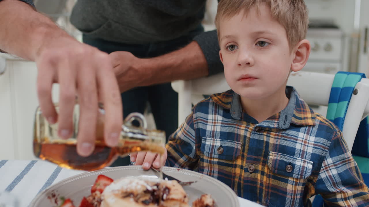 padre che prepara i waffle per la colazione per il figlio ragazzo carino che si gode un delizioso pasto fatto in casa in cucina a casa 4k