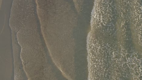 Aerial-ascending-slowly-on-rolling-waves-breaking-on-sandy-sunlit-beach