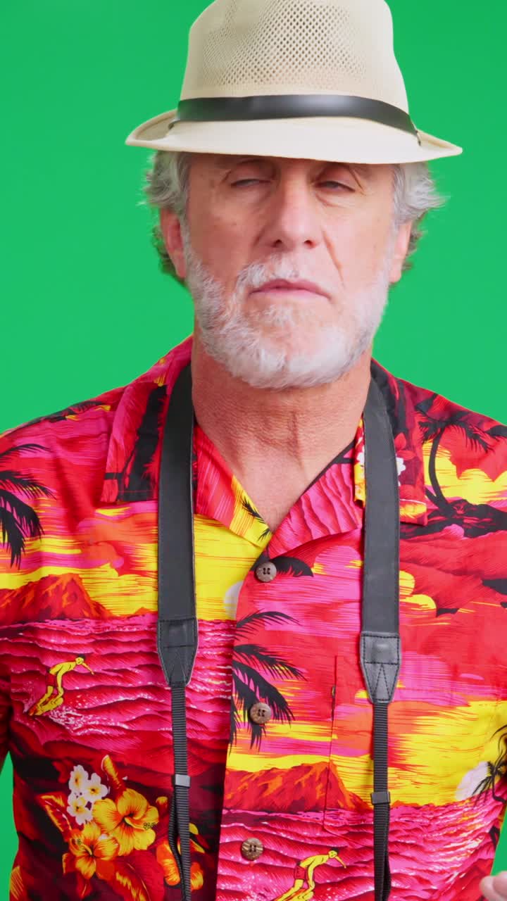 Uomo anziano con camicia hawaiana che usa lo smartphone su schermo verde.