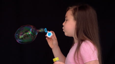 cheerful girl making big bubbles