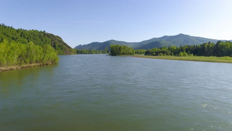 a river flowing through a valley, surrounded by mountains and trees