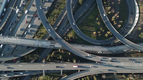 Una-Vista-Panorámica-De-Arriba-Hacia-Abajo-De-Una-Carretera-Compleja-Y-Entrelazada-Con-Rampas-De-Entrada-Y-Salida-Interestatales-Llenas-De-Tráfico-De-Automóviles