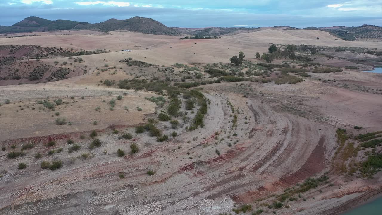 Drone footage revealing dried out riverbed and arid, rolling hills, showing severe impact of drought and water scarcity in Andalusia, Spain