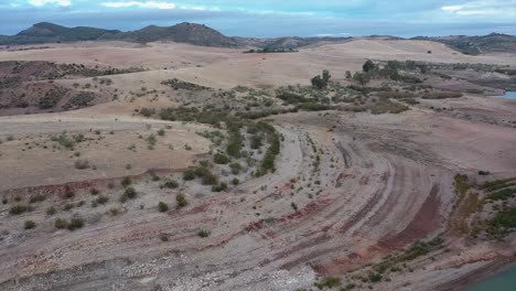 drone footage revealing dried out riverbed and arid, rolling hills, showing severe impact of drought and water scarcity in andalusia, spain