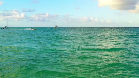 Pequeño-Bote-A-Motor-Que-Viaja-En-Aguas-Verdes-Del-Océano-En-Un-Día-Soleado,-Punta-Cana,-República-Dominicana,-Por-Encima-Del-Enfoque-Aéreo