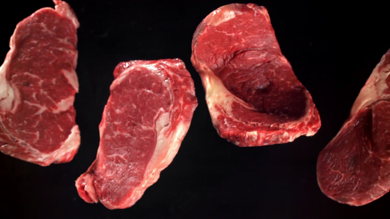 Four Raw Beef Steaks on a Black Background