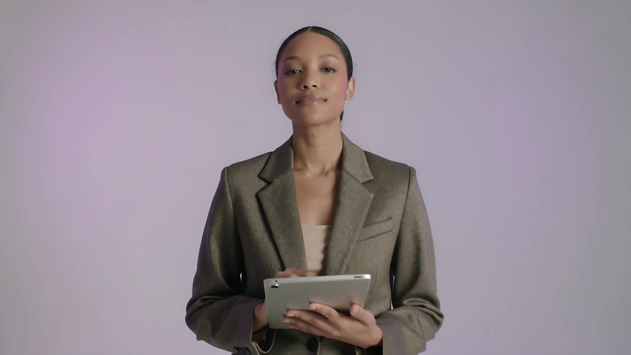 Pulling back camera presenter holding tablet tapping scrolling presenting in studio with blazer