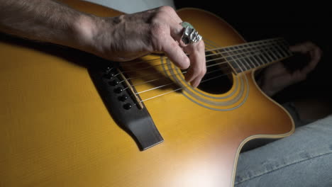 amputee playing acoustic guitar with close up on missing finger