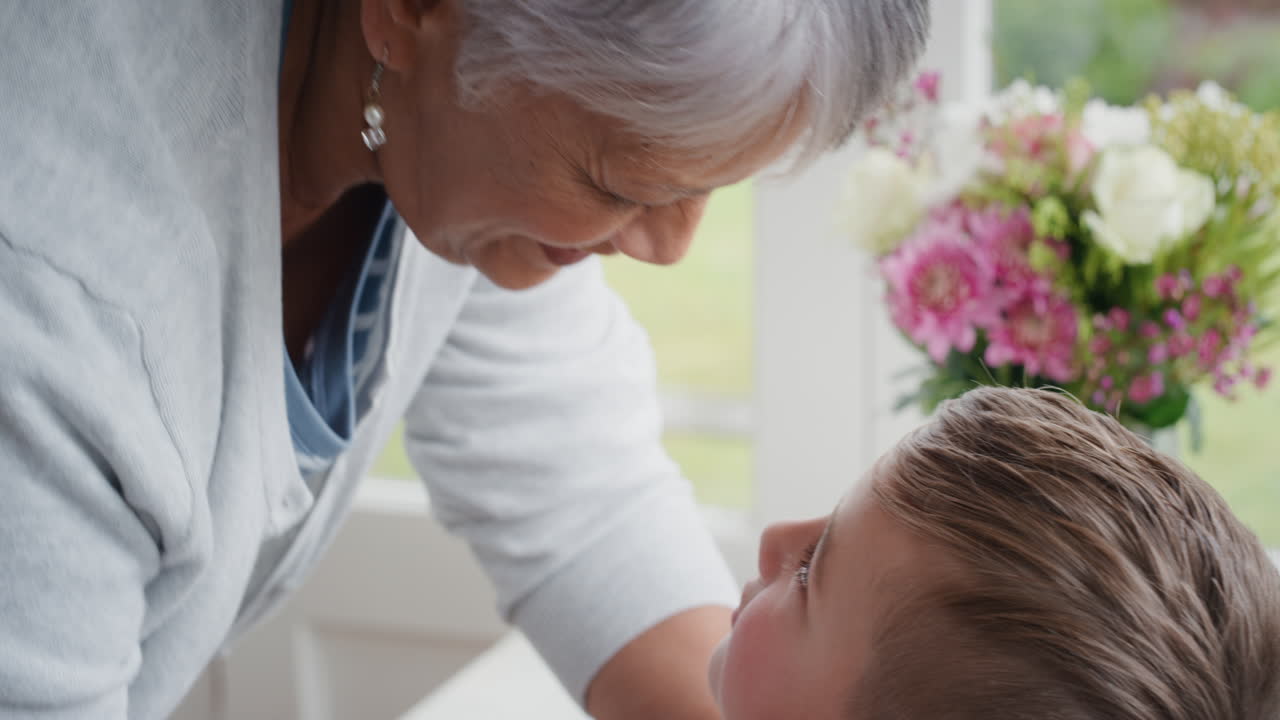 할머니는 작은 소년을 이마에 부드럽게 키스하고 손자에 대한 사랑을 보여주고 자랑스러운 할머니는 손자에 대한 사랑을 느끼고 있습니다.