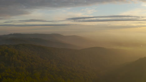 Slow-reveal-above-Olinda,-Victoria,-Australia-township-with-stunning-afternoon-light-pouring-through-clouds