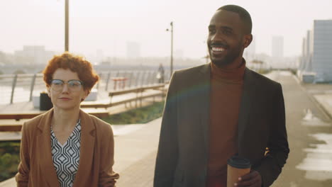 black businessman and caucasian businesswoman walking on street and talking