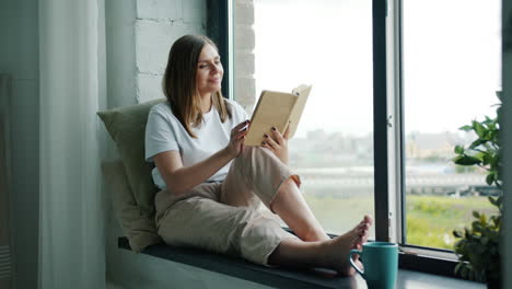 mujer leyendo un libro junto a la ventana