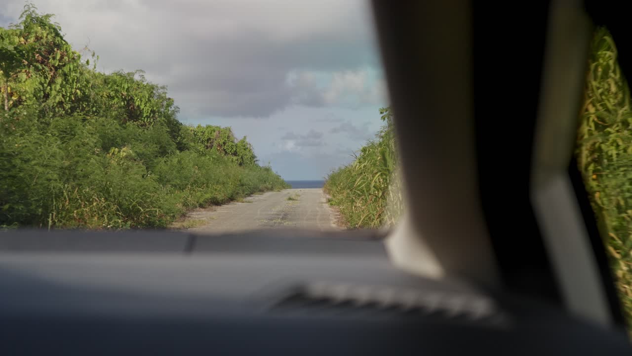 Car moving along a rocky and isolated road, overlooking the ocean