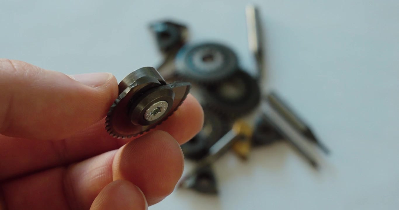 Primo piano di una mini mola da taglio rotta tenuta in mano, che mostra danni all'utensile, usura, riparazione, manutenzione dell'officina e guasto di attrezzature industriali.