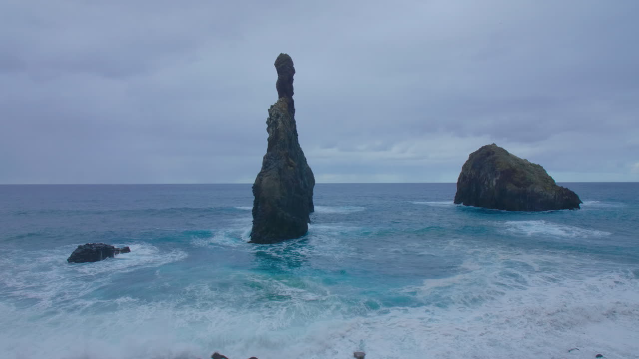 Ribeira da Janela, Madeira. Roca de Porto Moniz, Seixal, Madeira, con el mar agitado y olas en una playa inquieta en un día nublado.