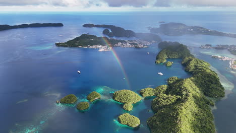 cinematic drone shot circling and revealing the pristine turquoise sea and lush islets around palau with a bright rainbow shining. wide cinematic aerial shot