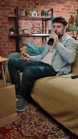 man relaxing on couch, watching tv and eating