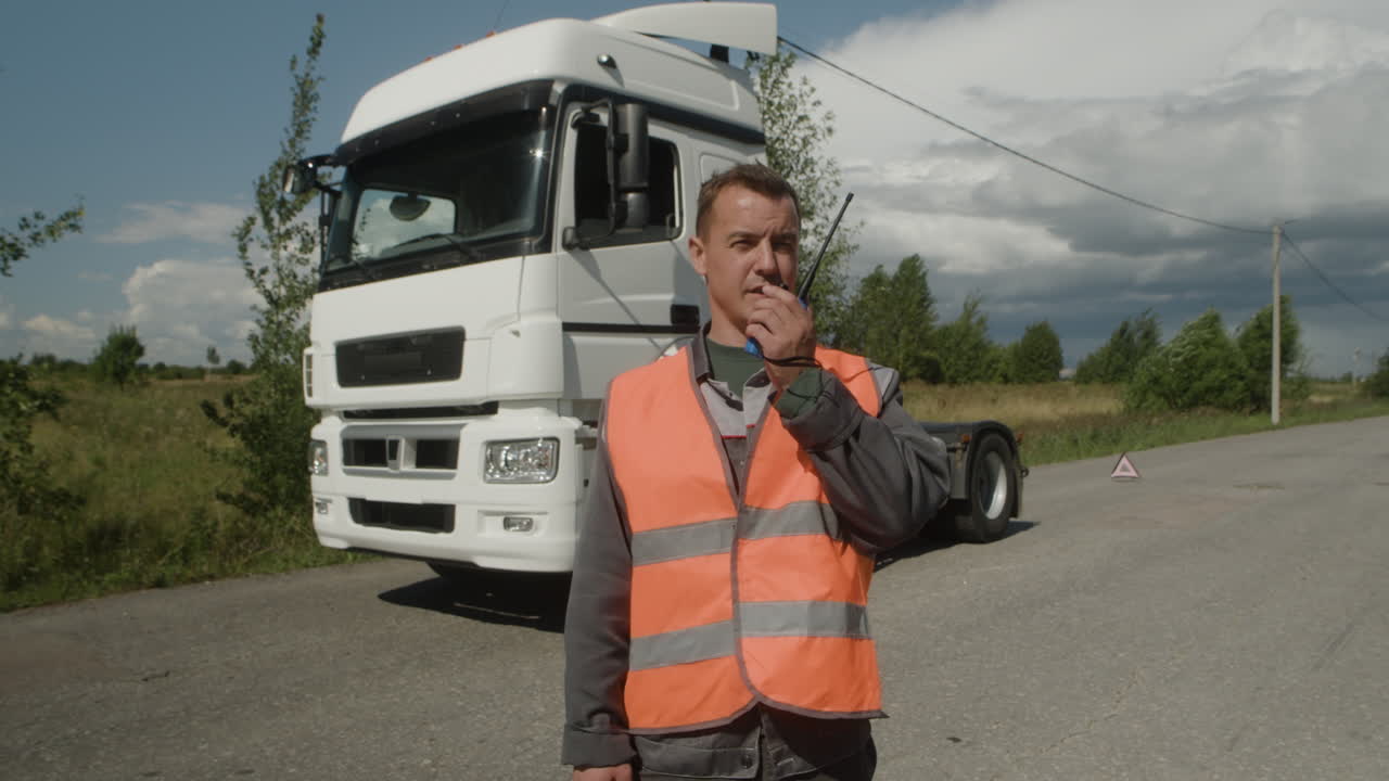 Truck Driver Communicating on Walkie Talkie Near Semi-Truck