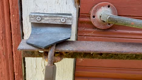 4k 60fps old padlock and metal bar on red wooden shack - truck shot