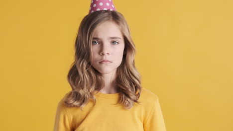 sad teenage caucasian girl wearing a party hat.