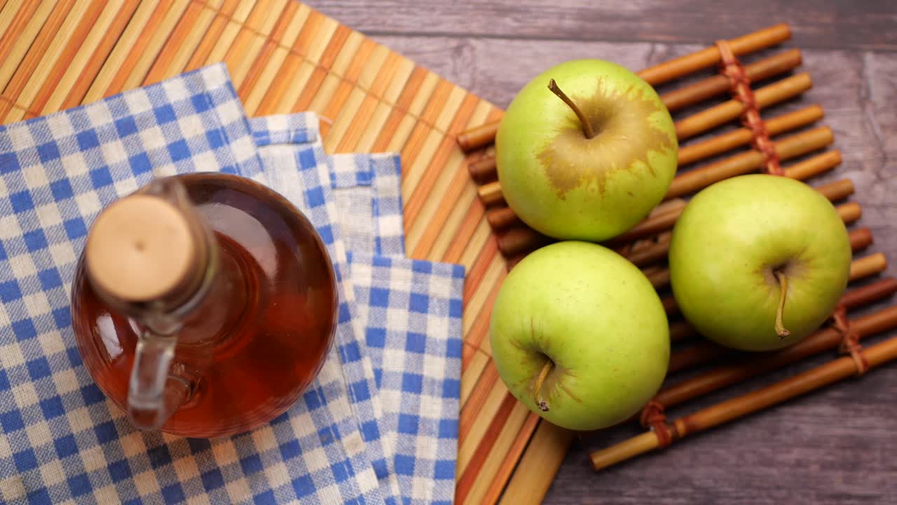 vinagre de manzana en una botella de vidrio con manzana verde fresca en la mesa ,