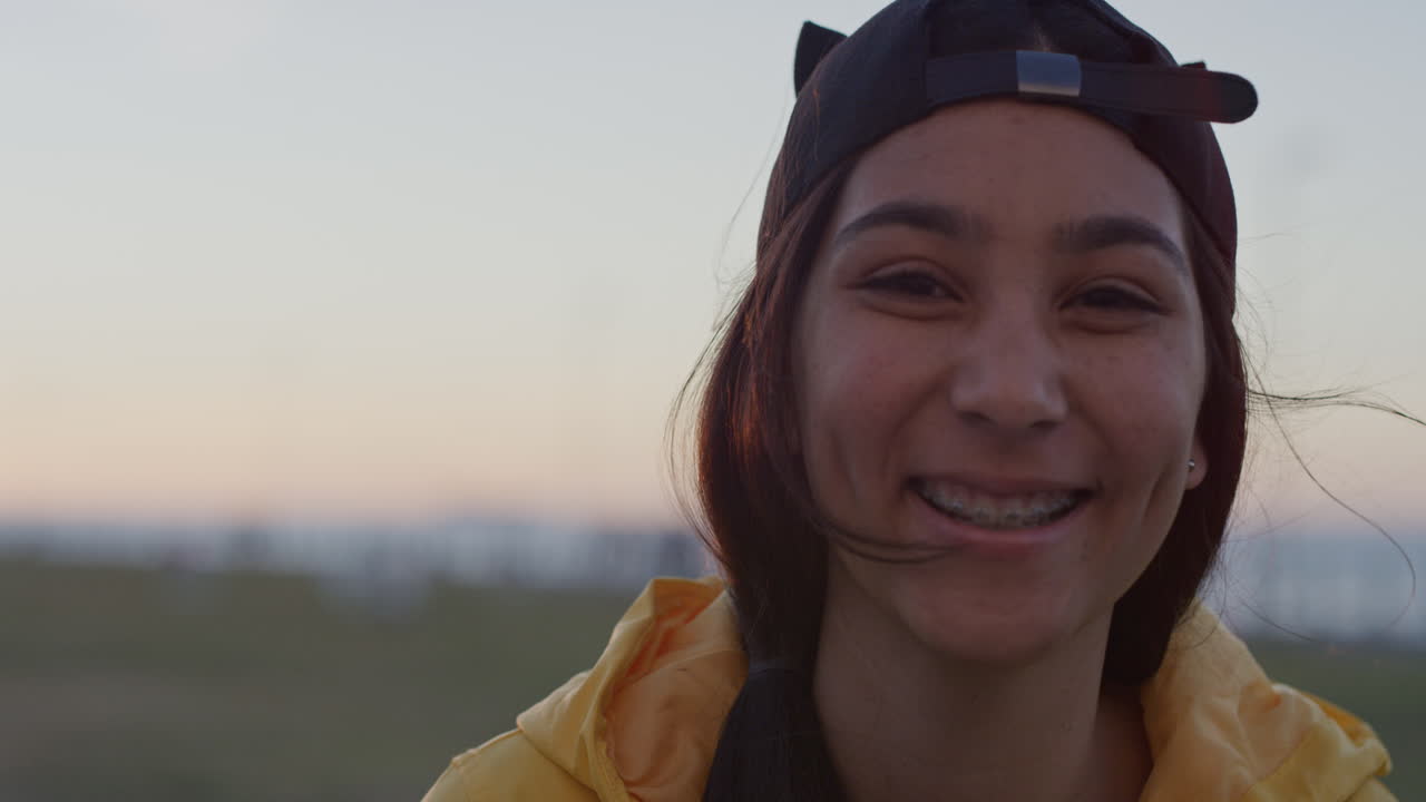 retrato en primer plano de una adolescente riendo alegremente mirando a la cámara con aparatos ortopédicos disfrutando del parque al atardecer en cámara lenta