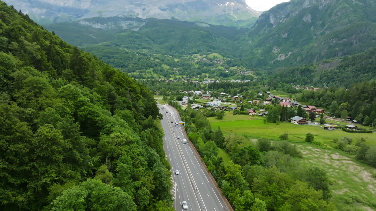 Aerial ascending shot of traffic on road N205 and the Servoz town, in France