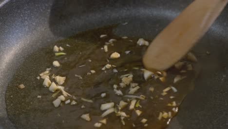 close up of fresh garlic being stirred in a cooking pan